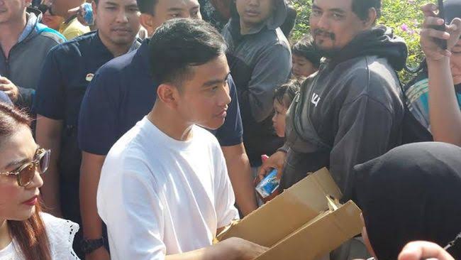 Gibran Rakabuming Raka saat membagikan susu kepada warga (Foto: CNN Indonesia, 2023).