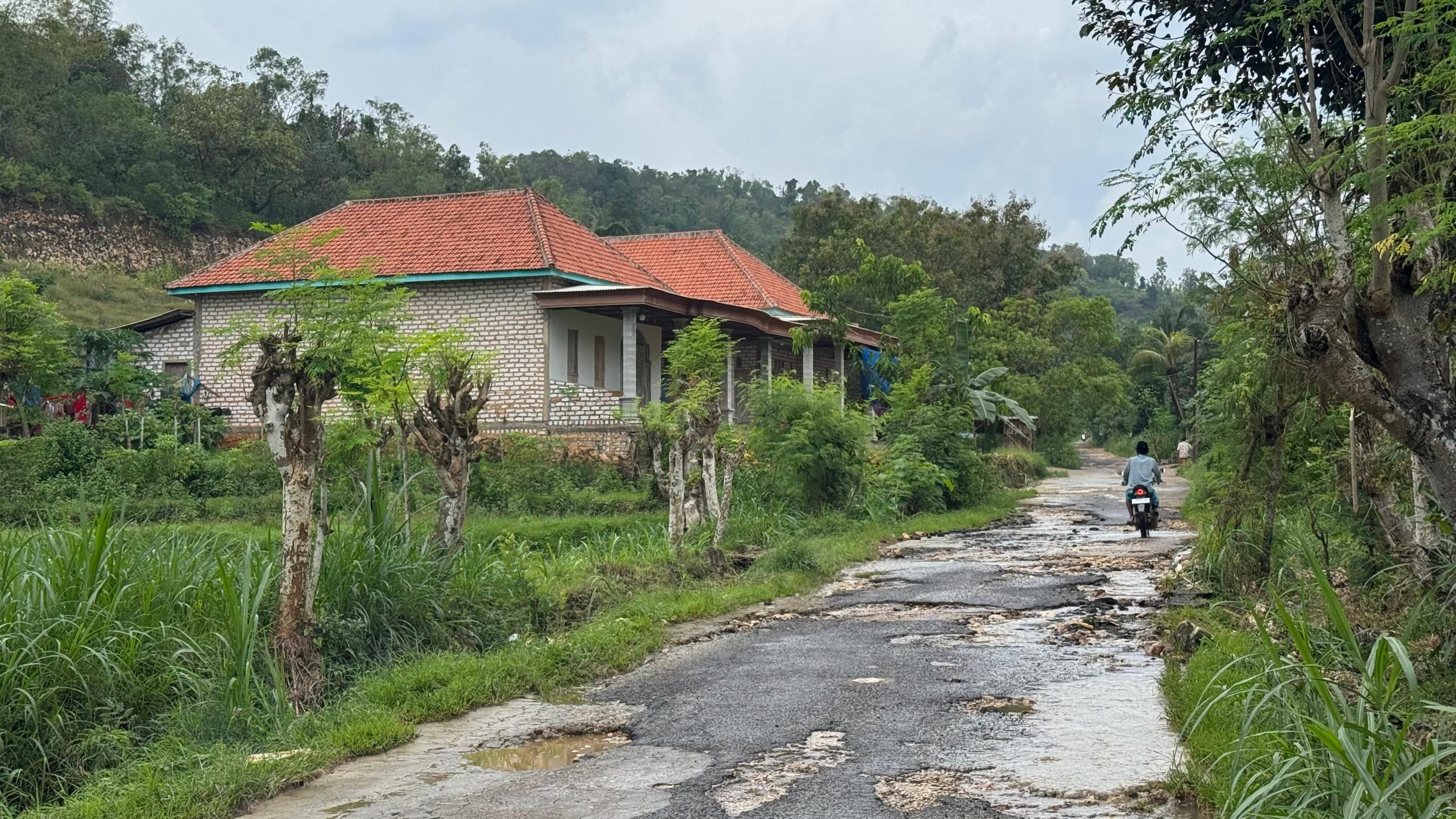 Pengendara R2 melintas dijalan Batulenger-Karangpenang dengan penampakan jalan yang rusak parah